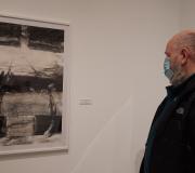 Un asistente ao acto de presentación contempla un dos debuxos da exposición de Mingos Teixeira.