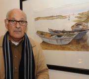 El pintor al lado de una de sus obras expuestas