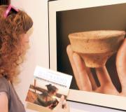 Unha moza observa uhna imaxe das pezas atopadas na excavación