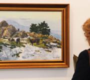 Unha muller contempla un dos cadros da exposición de M. Ortiz