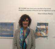 2. A artista Isabel Pintado entre unha das súas paisaxes e un libro intervido.