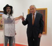 O pintor Carlos Santos pasa ao delegado da Xunta, José Ramón Ónega, o pincel que usou nun xesto en memoria do desastre cultural ocorrido en Brasil.