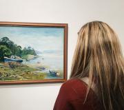 5. Unha moza contempla unha das mariñas da mostra de Leyra Domíngez.